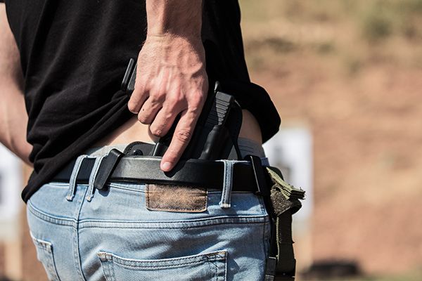 A man putting a gun in the back of his pants