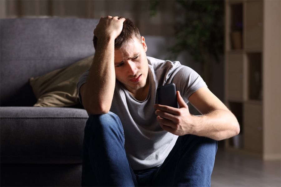 A man looking distressed and staring at his phone