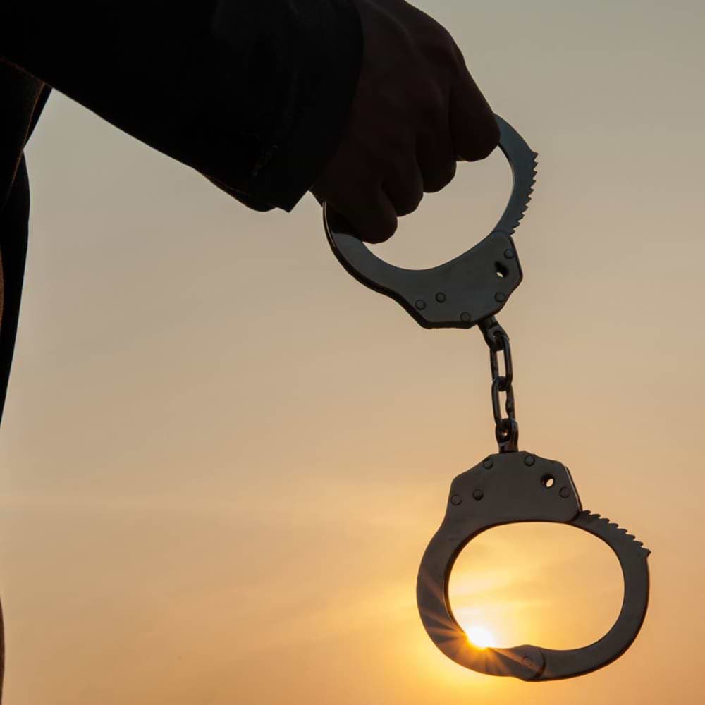 Pair of handcuffs dangling from hand